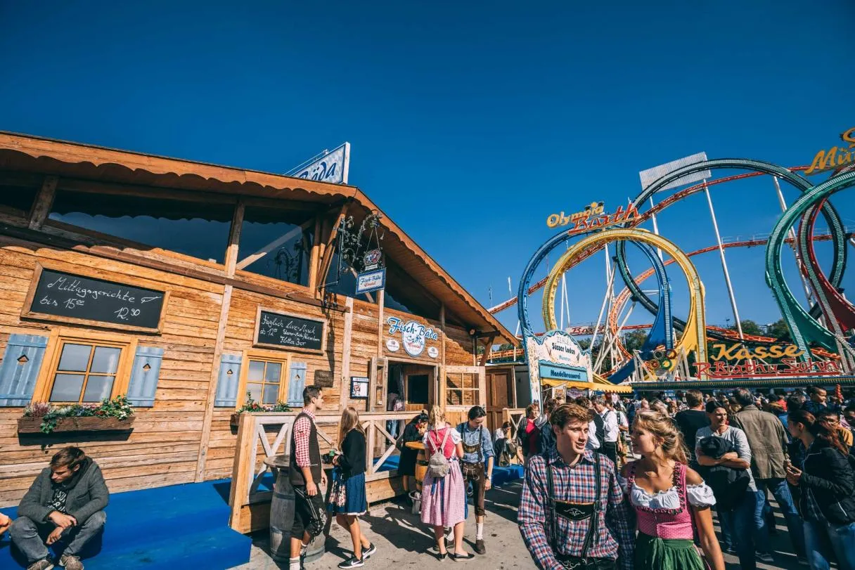 A rustic Oktoberfest tent named Fisch-Bäda with weathered wooden furniture, smoke accents, and a sign displaying technical specs like R30 and 15°, evoking a blend of Bavarian tradition and industrial charm.
